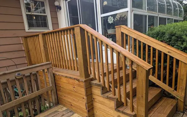 New wood deck stairs, landing and railings with square balusters leading up to a back door