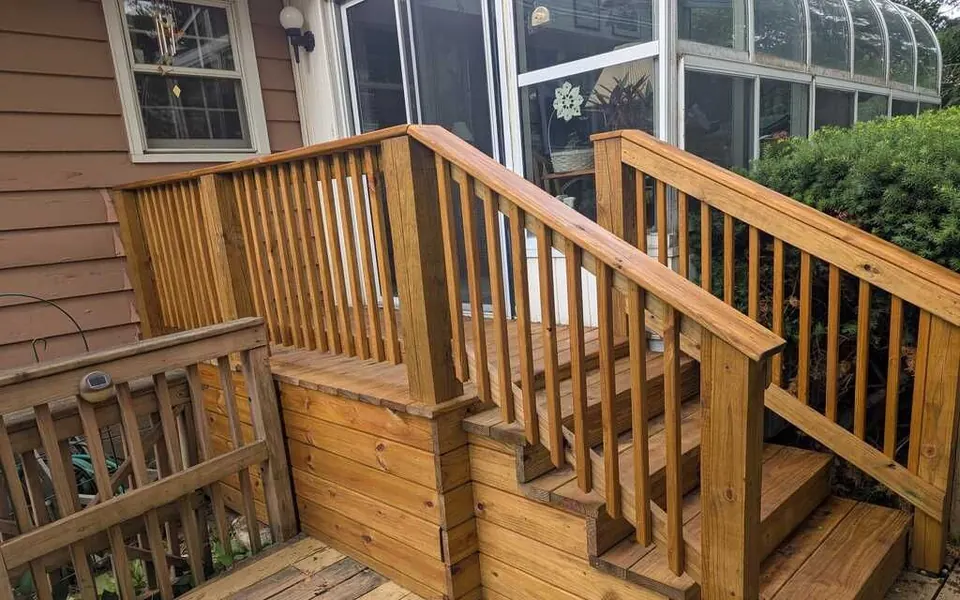 New wood deck stairs, landing and railings with square balusters leading up to a back door