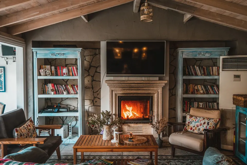 Warm lower-level living room with a fireplace, built-in shelving and a wood beamed ceiling